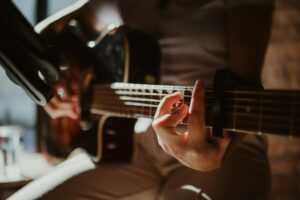 Close up of a man holding a chord on a acoustic guitar