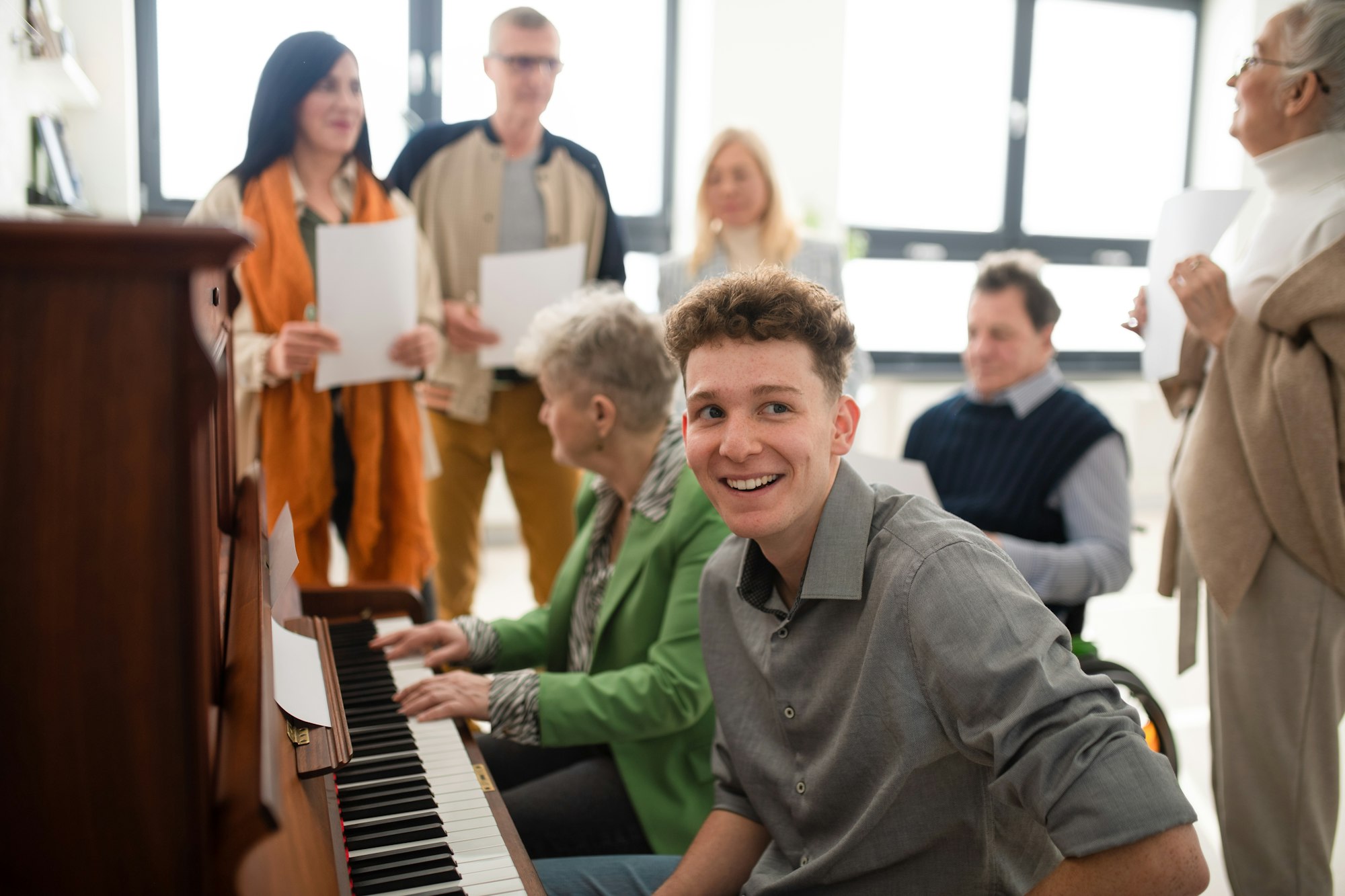 Group of seniors with young teacher singing together at choir rehearsal