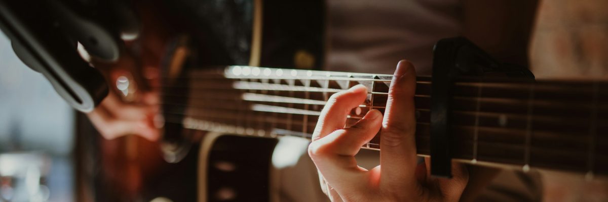 Close up of a man holding a chord on a acoustic guitar